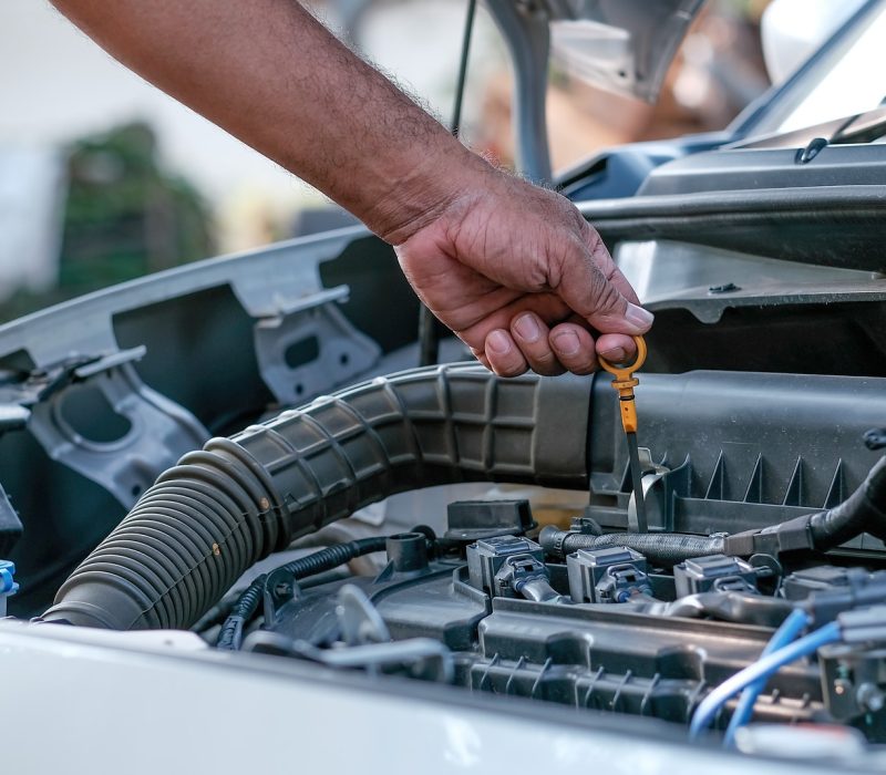 Hands of automotive mechanic check and inspecting the engine of the car.